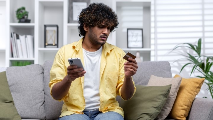 Confused man with phone and credit card