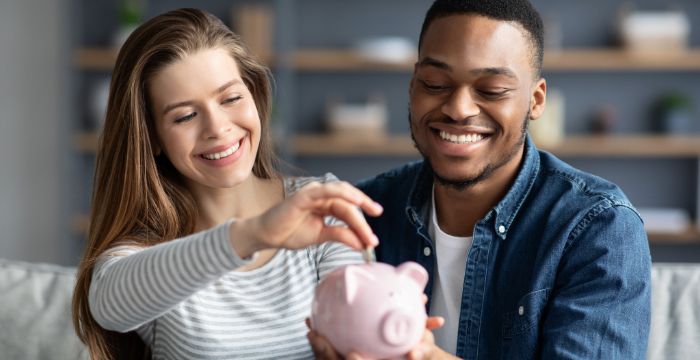 Couple putting cash into a piggy bank