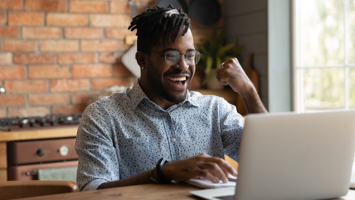 Person looking at laptop with excited expression.